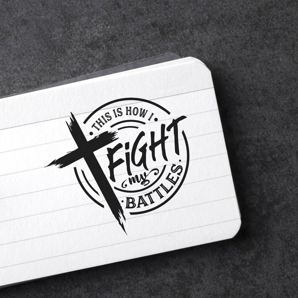 Black circular rubber stamp seal on white lined card with This is how I fight my battles text on a dark background.