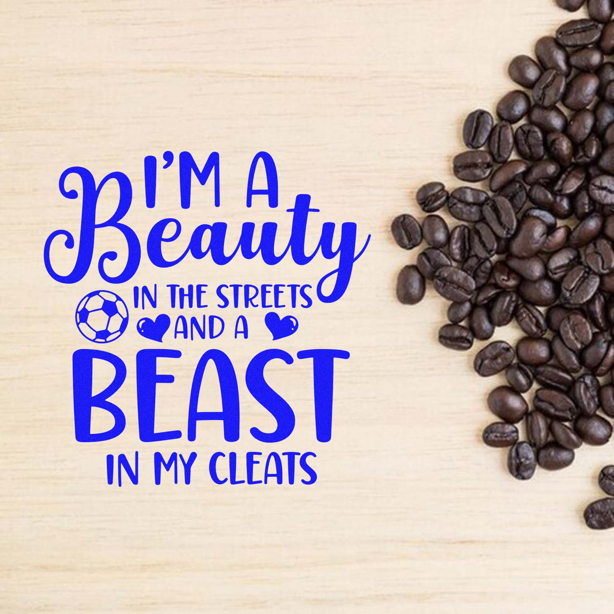 Blue custom stamp seal reading Im a Beauty in the Streets and a BEAST in My Cleats, with coffee beans on a beige wood background.