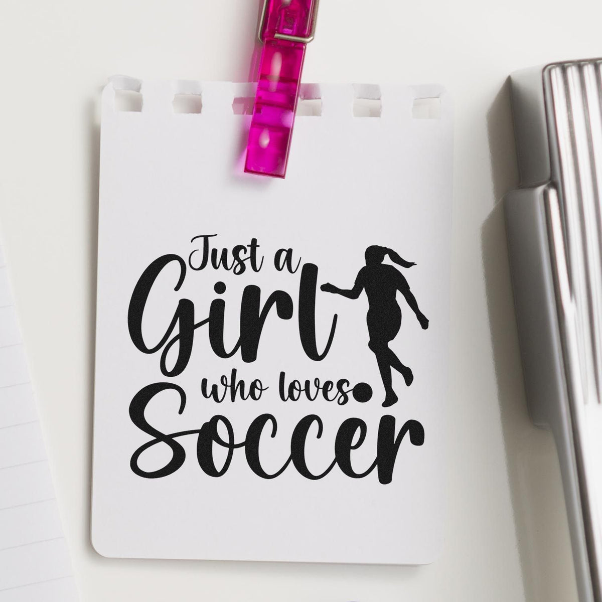 White stamp seal card with black "Just a Girl who loves Soccer" text, female soccer silhouette, pink clip, and silver binder.