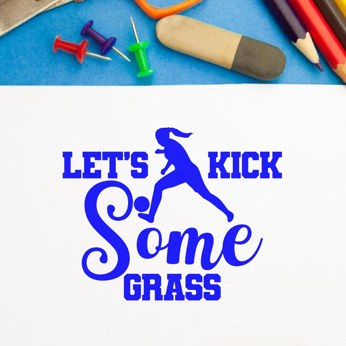 Blue custom stamp and seal design with a soccer player silhouette and LETS KICK Some GRASS on white paper.