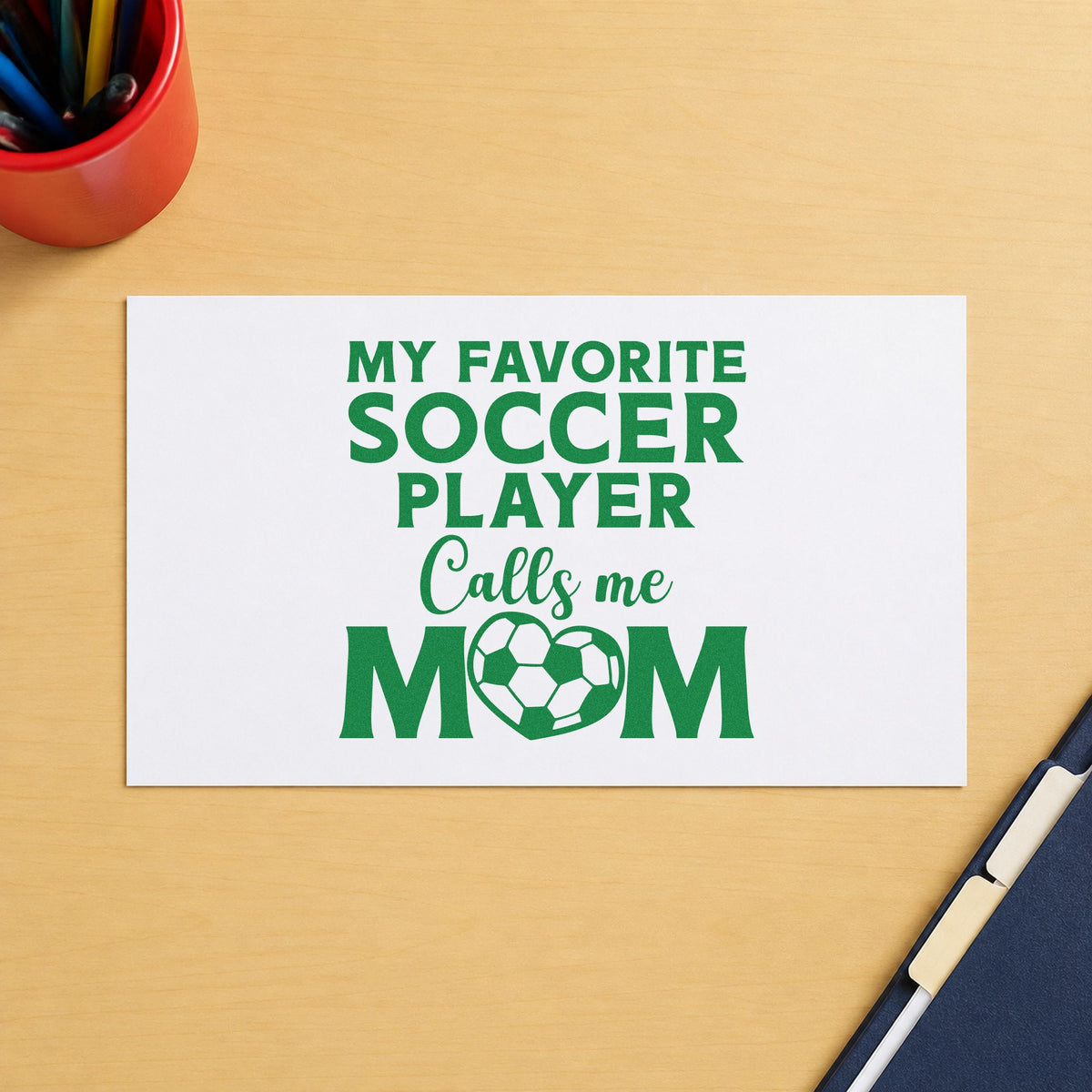 Favorite Soccer Player Calls Me Mom craft stamp imprint in green ink on a handmade project, one idea being roster binder pages.