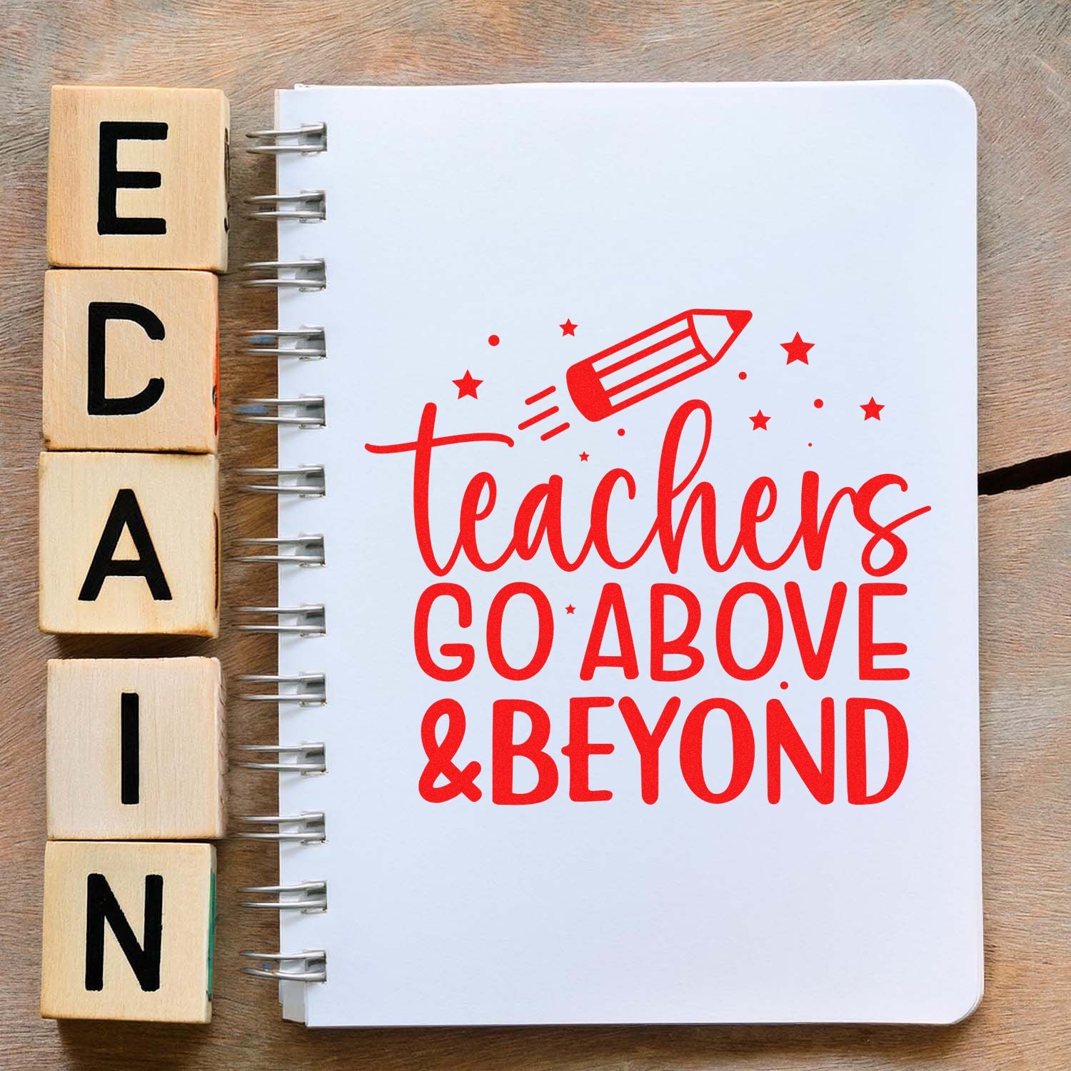 Wooden alphabet stamp blocks beside a white notebook with a red teacher logo, pencil, stars, and Teachers Go Above & Beyond text.