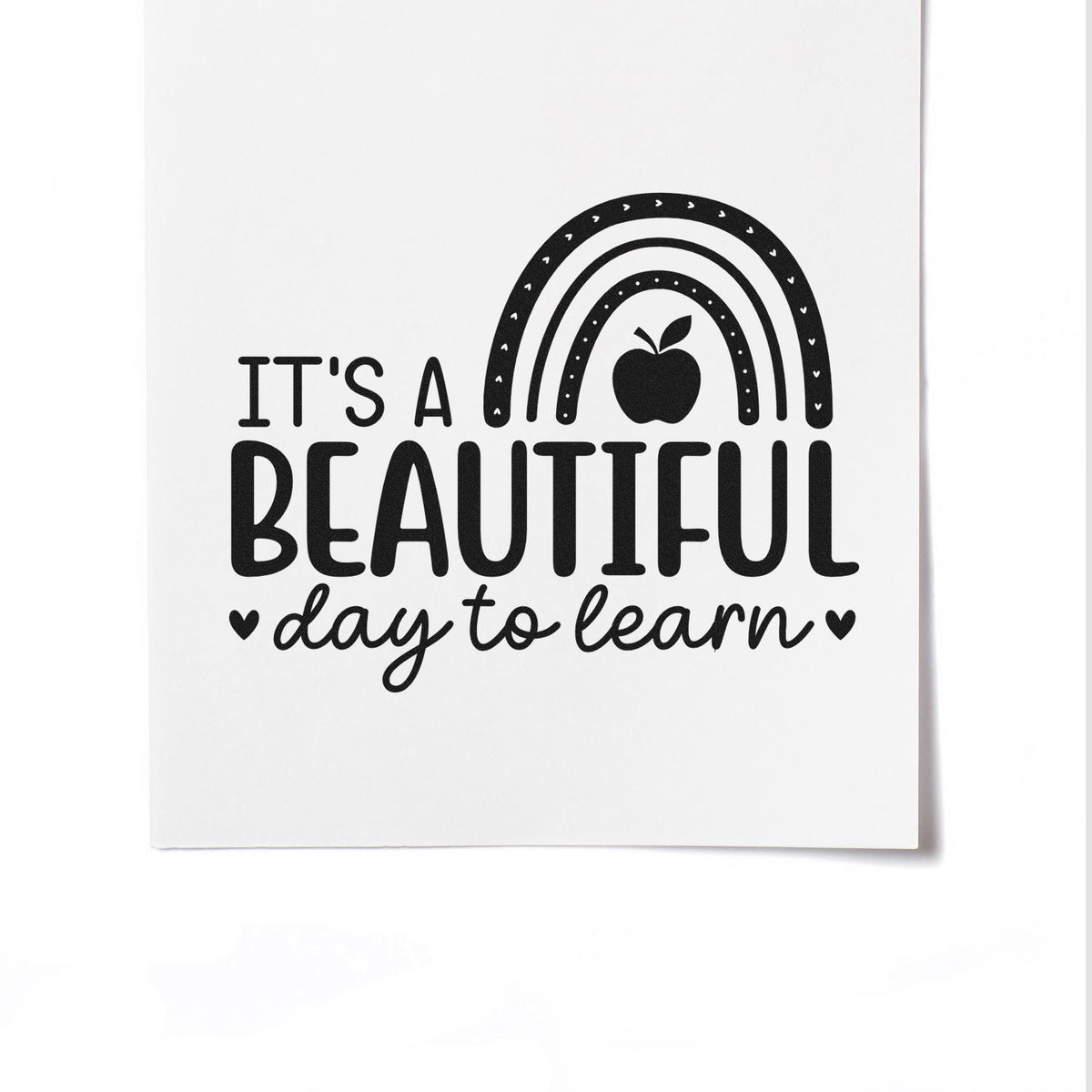 Black classroom stamp and seal design on white, with rainbow, apple and hearts, reading Its a beautiful day to learn.