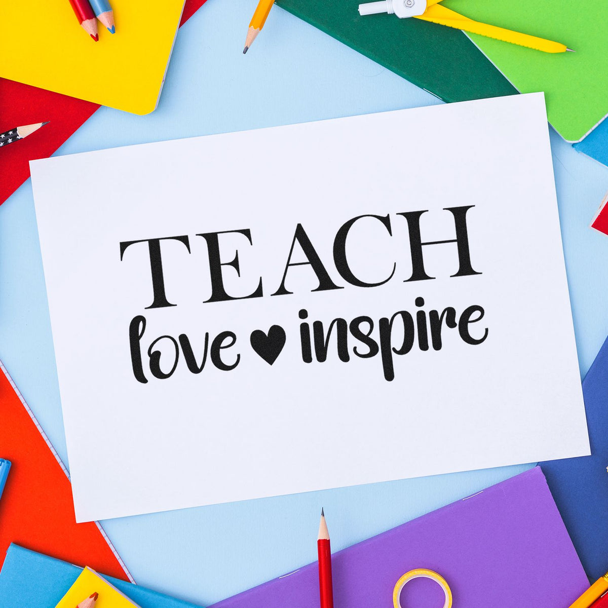 Teacher stamp and seal reading TEACH love inspire on white card, surrounded by colorful pencils and notebooks.