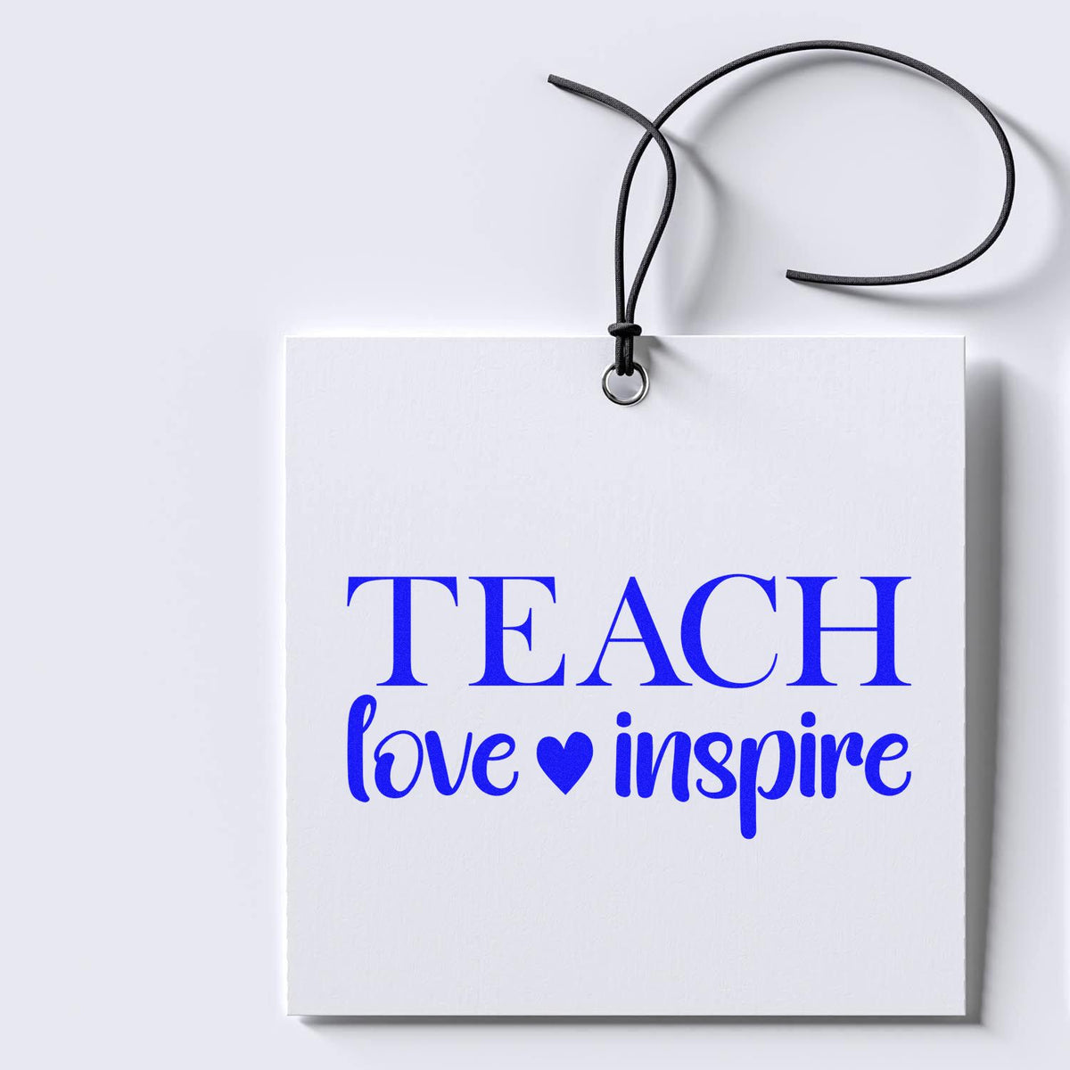 White teacher gift tag with black cord and blue TEACH love inspire lettering, stamped-seal style stationery design.