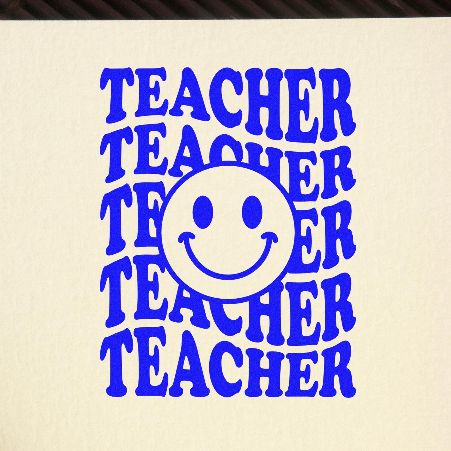 Blue TEACHER stamp seal design with repeated bold text and a smiley face on a cream background.