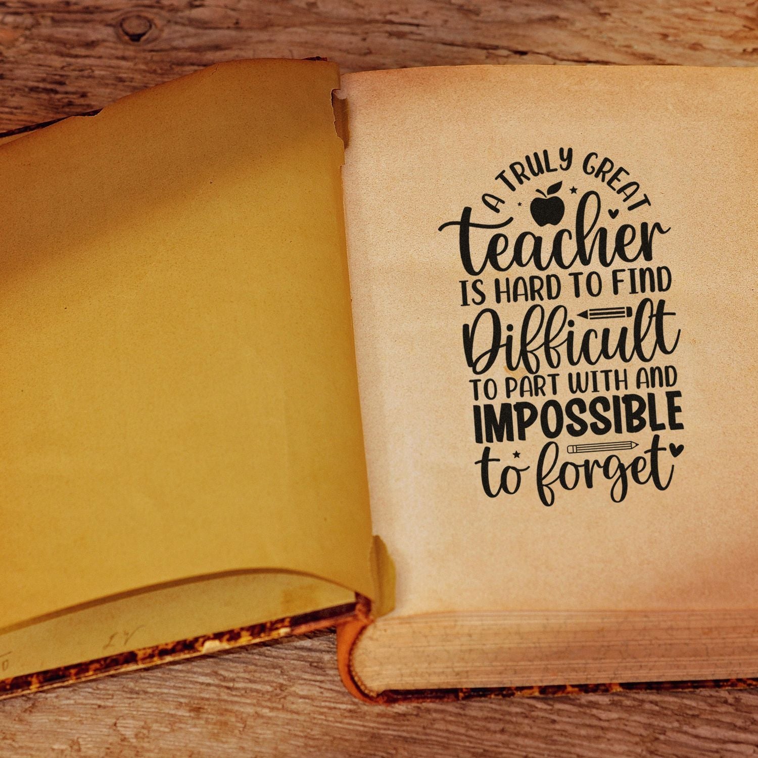 Black teacher stamp on cream paper with gold-toned seal-style page, set on rustic wood.