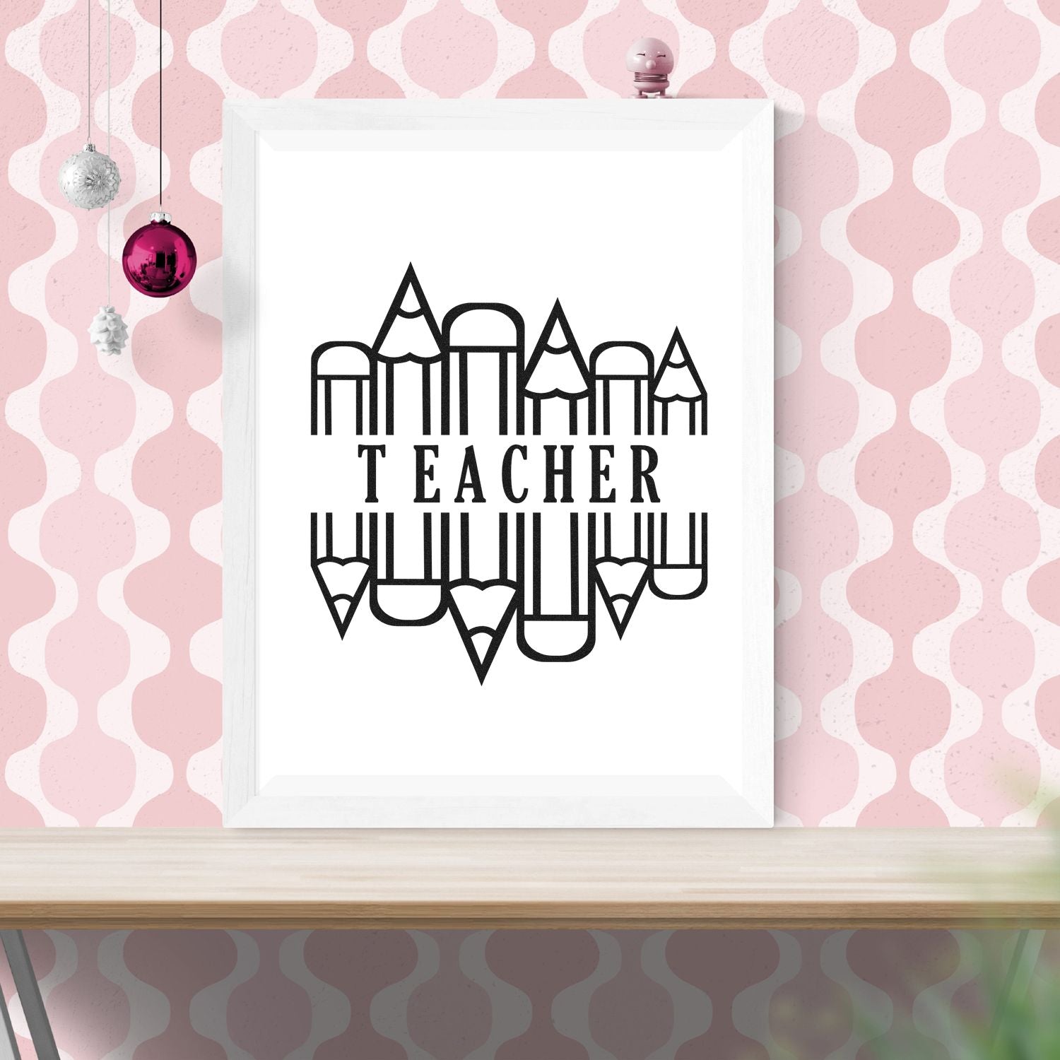 Teacher stamp and seal design with black pencil-circle logo on a white frame, set against a pink patterned wall with hanging ornaments.