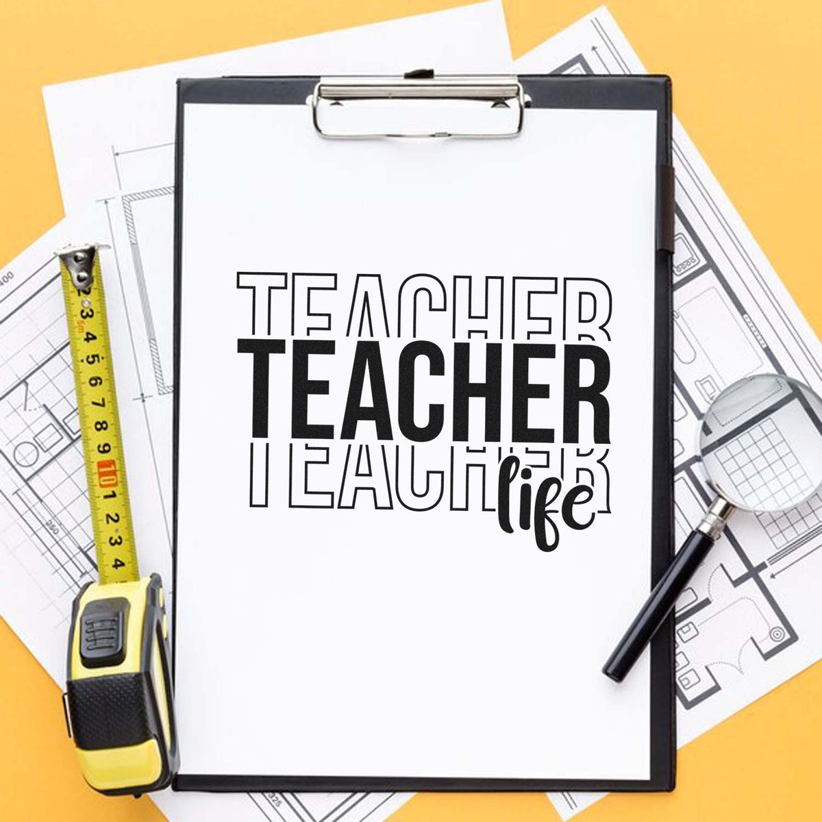 Teacher life rubber stamp and seal on clipboard, with yellow tape measure, magnifier, and blueprint sheets.