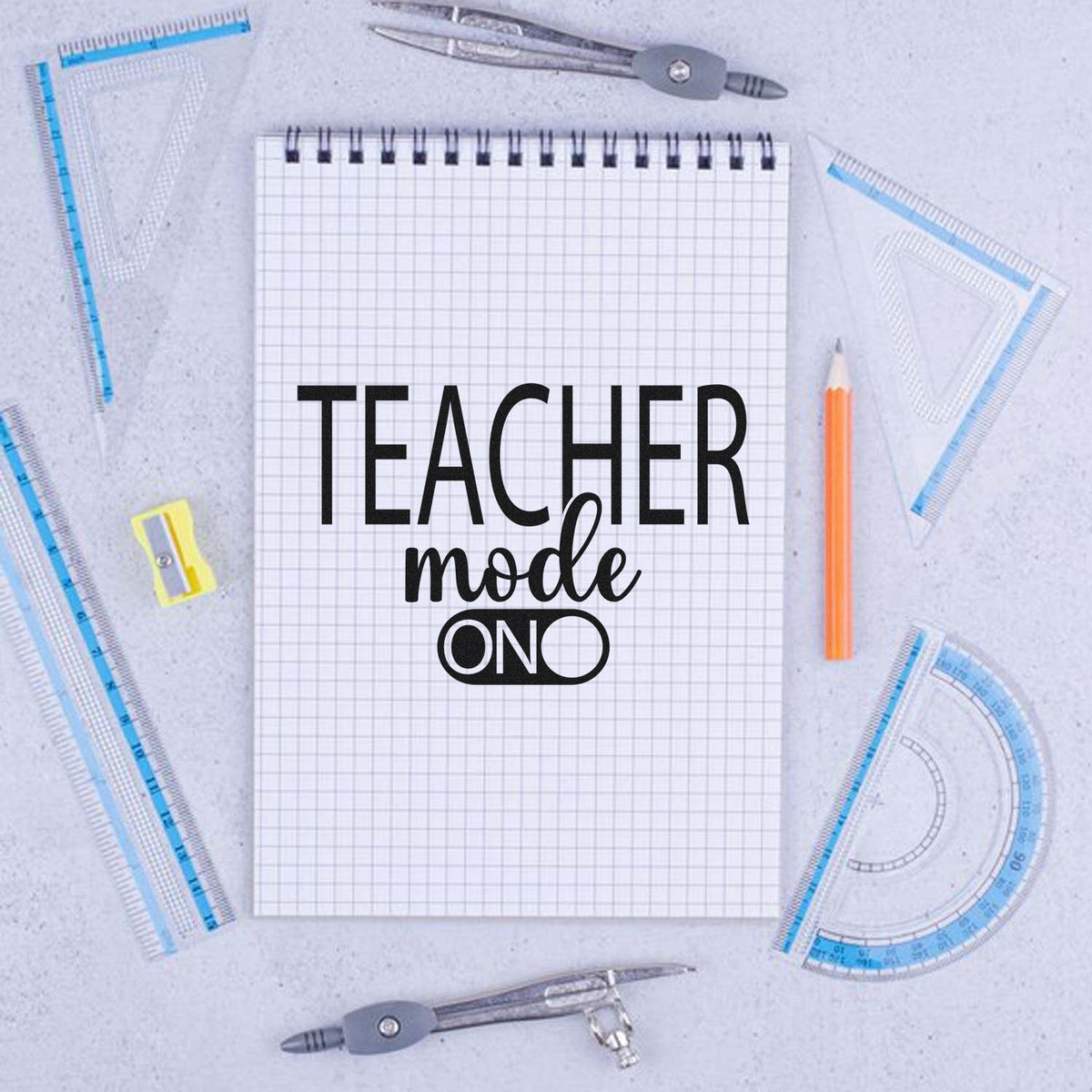 Teacher Mode On stamp/seal design on a grid notebook, with blue rulers, orange pencil, and silver compasses on a light gray background.