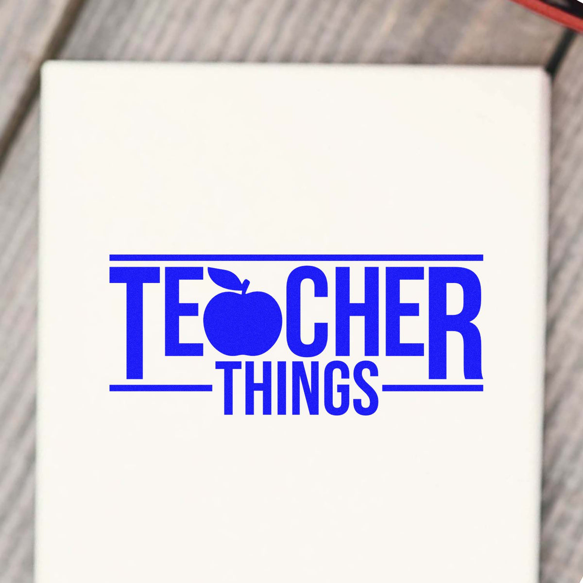 White stamp seal with bold blue TEACHER THINGS text and apple icon