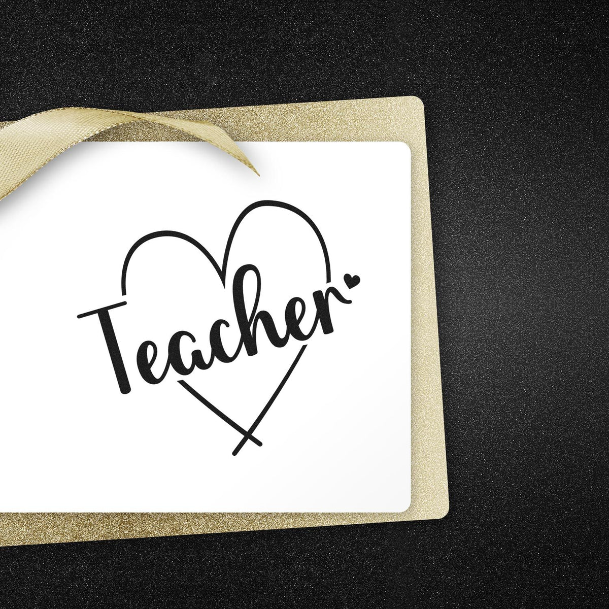 Teacher heart stamp in black on a white card with gold glitter seal border and ribbon on a black textured background.