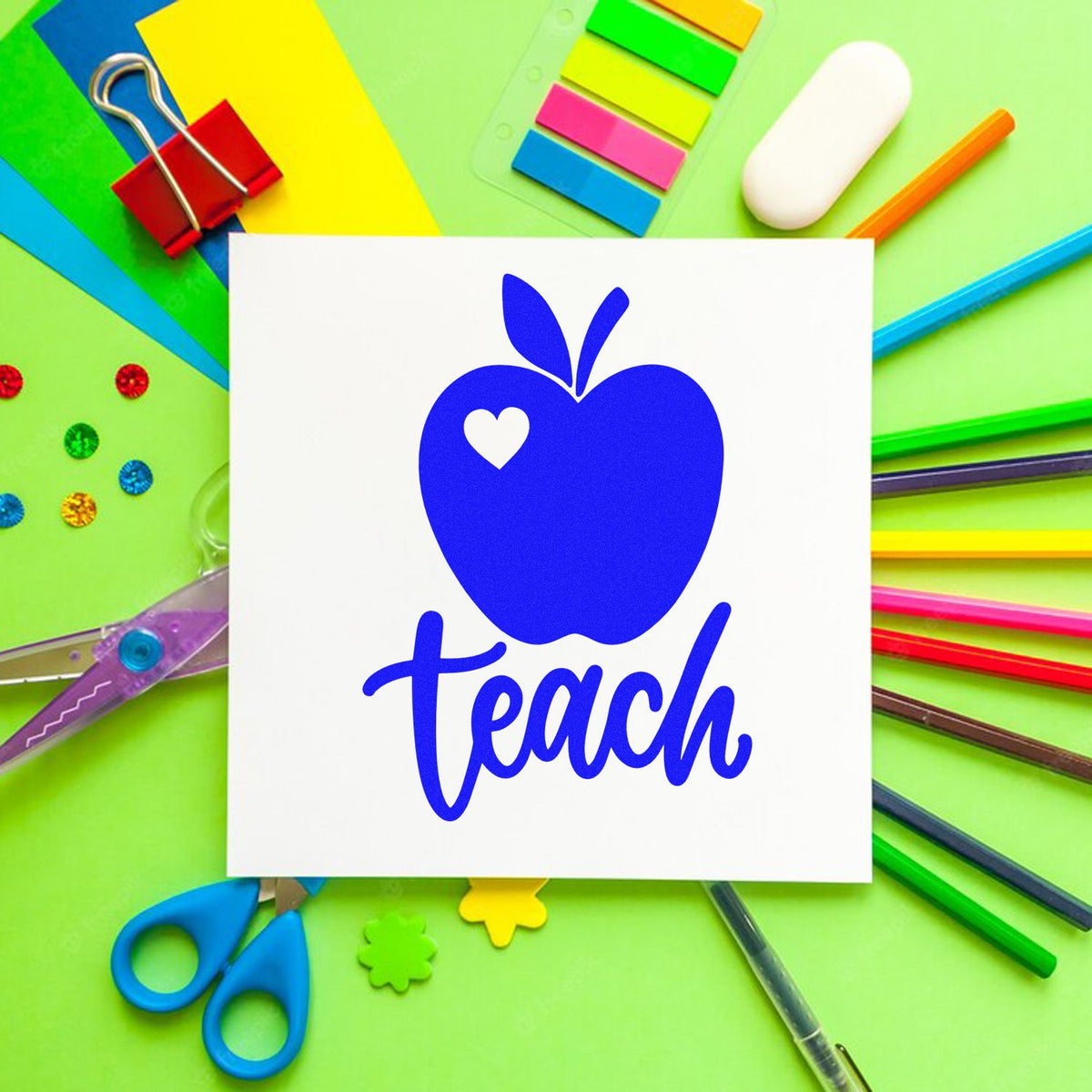 Blue apple teach stamp on white card, surrounded by colorful school supplies and seal samples on green background.