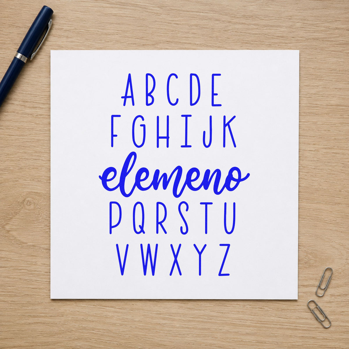 Alphabet Elemeno craft stamp imprinted in blue ink on paper, a design suited to book bin labels.