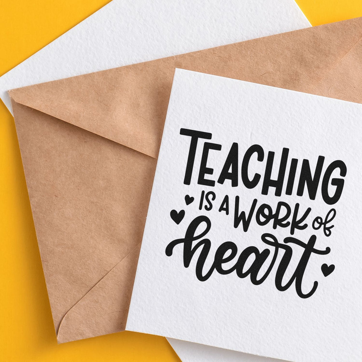 Custom teaching stamp and seal on white card over kraft envelope, with black Teaching is a work of heart text on yellow background.