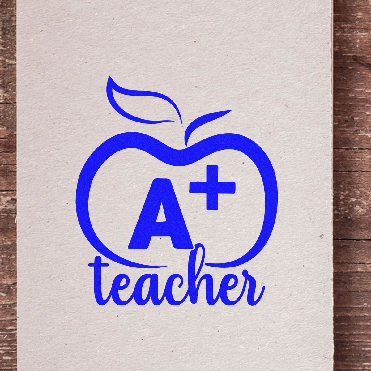 A Plus Teacher Outline Apple rubber stamp shown in blue ink, stamped for projects such as banquet seat tags.