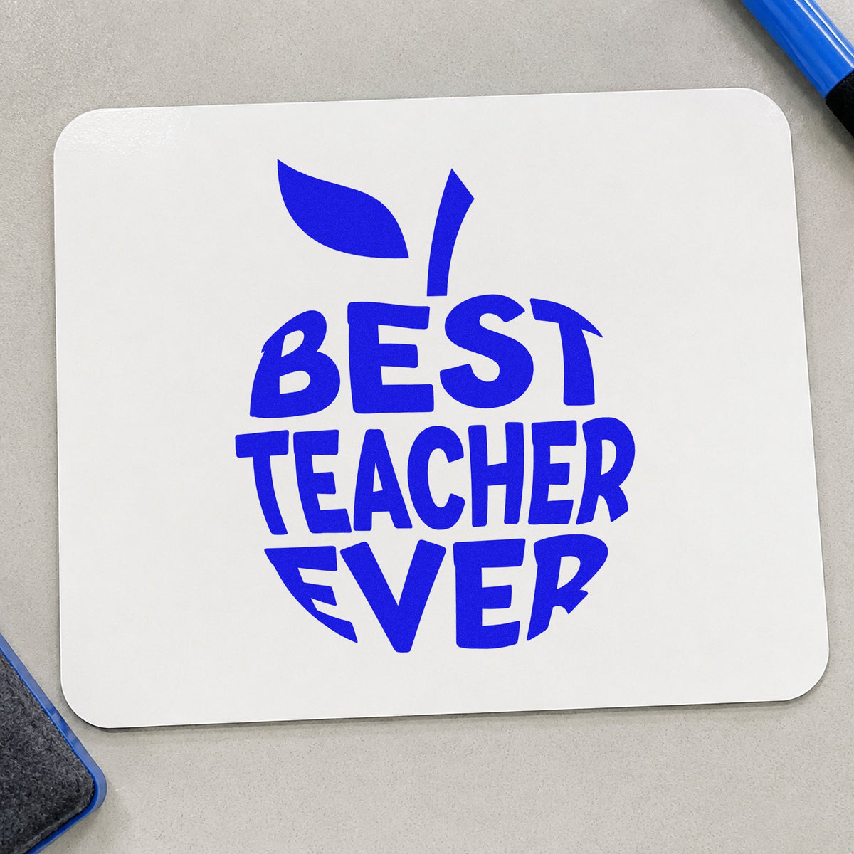 Best Teacher Ever Apple craft stamp imprinted in blue ink on paper, a design suited to gift box labels.