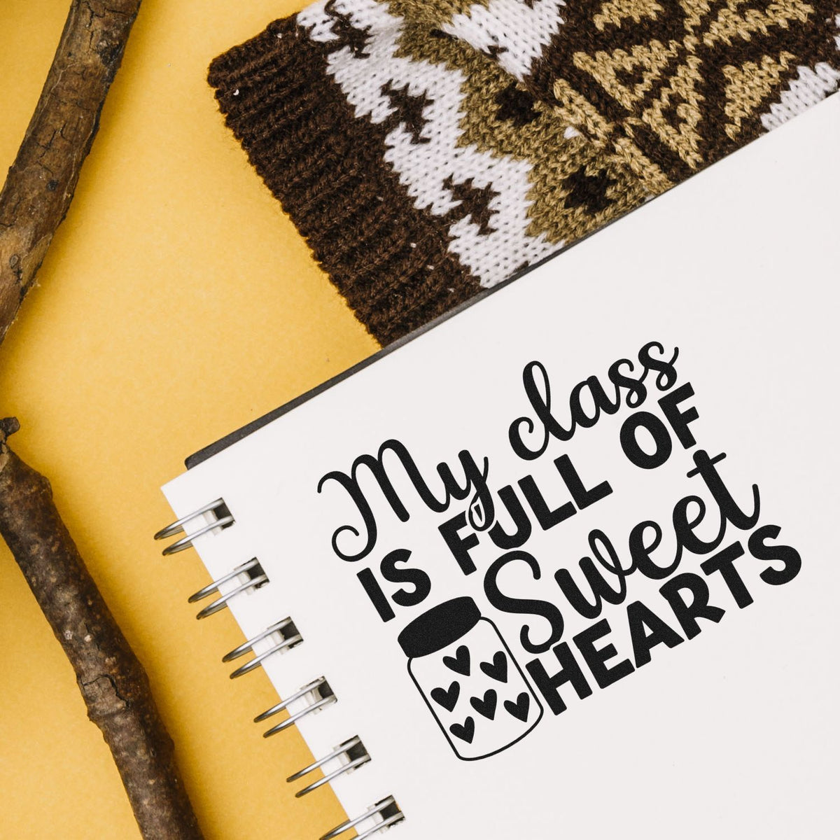 White spiral notebook featuring a black stamp-style seal, My class is full of sweet hearts, with heart jar icon on yellow.