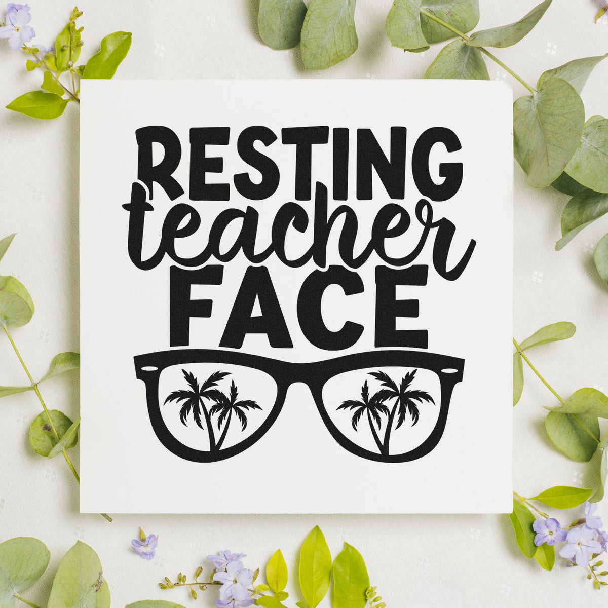 Black Resting Teacher Face stamp design with palm tree sunglasses on white, framed by green leaves and purple flowers.