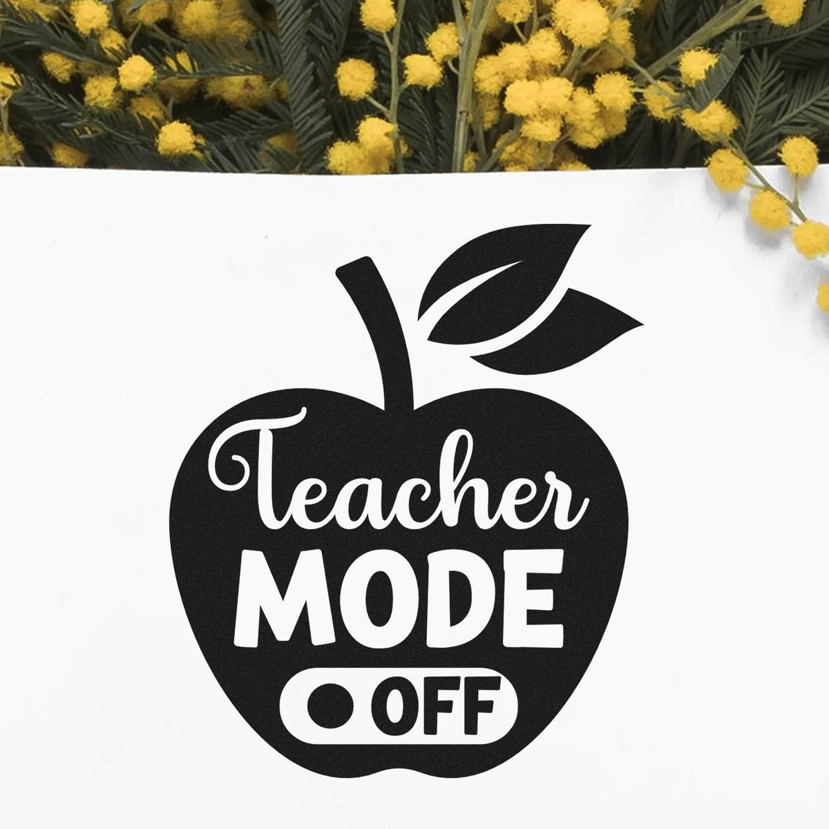Black apple-shaped teacher stamp seal with white Teacher Mode Off text on white, framed by yellow flowers.