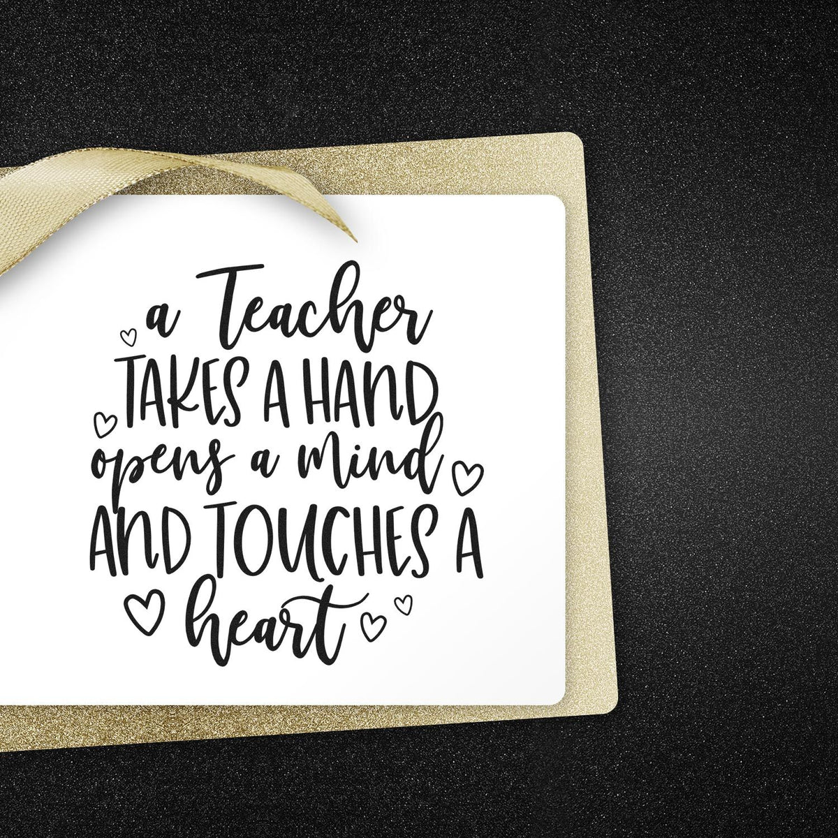 Black teacher stamp with heart accents on a white card, set on a gold glitter seal and black textured background.