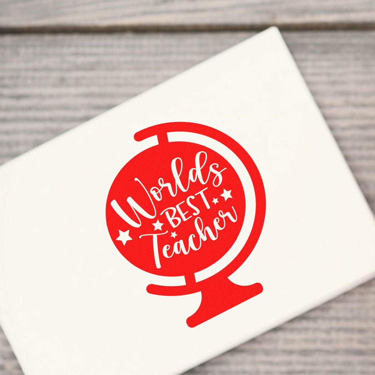 Red circular stamp seal with white Worlds Best Teacher text on a white card.