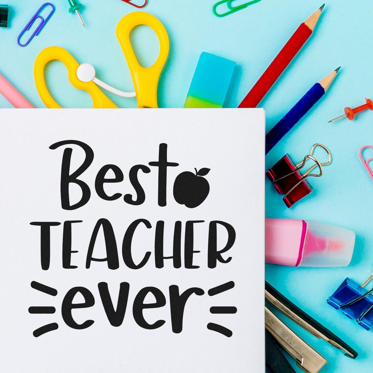 Colorful teacher stamp and seal supplies with a white Best Teacher ever card, pencils, clips, eraser, and binder clips.