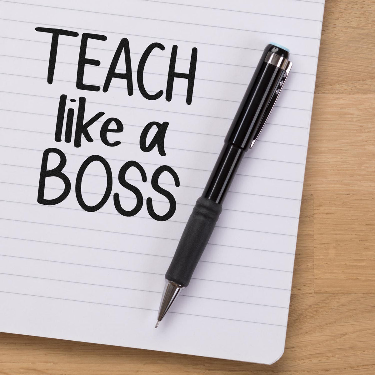 Black teacher stamp and seal pen on lined notebook reading TEACH like a BOSS.