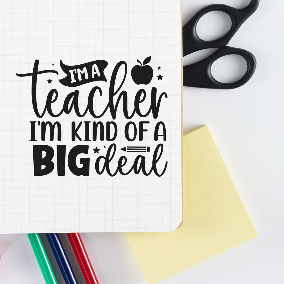 Black teacher stamp and seal design on white grid paper, with apple icon, scissors, yellow note, and red, blue, green pens.