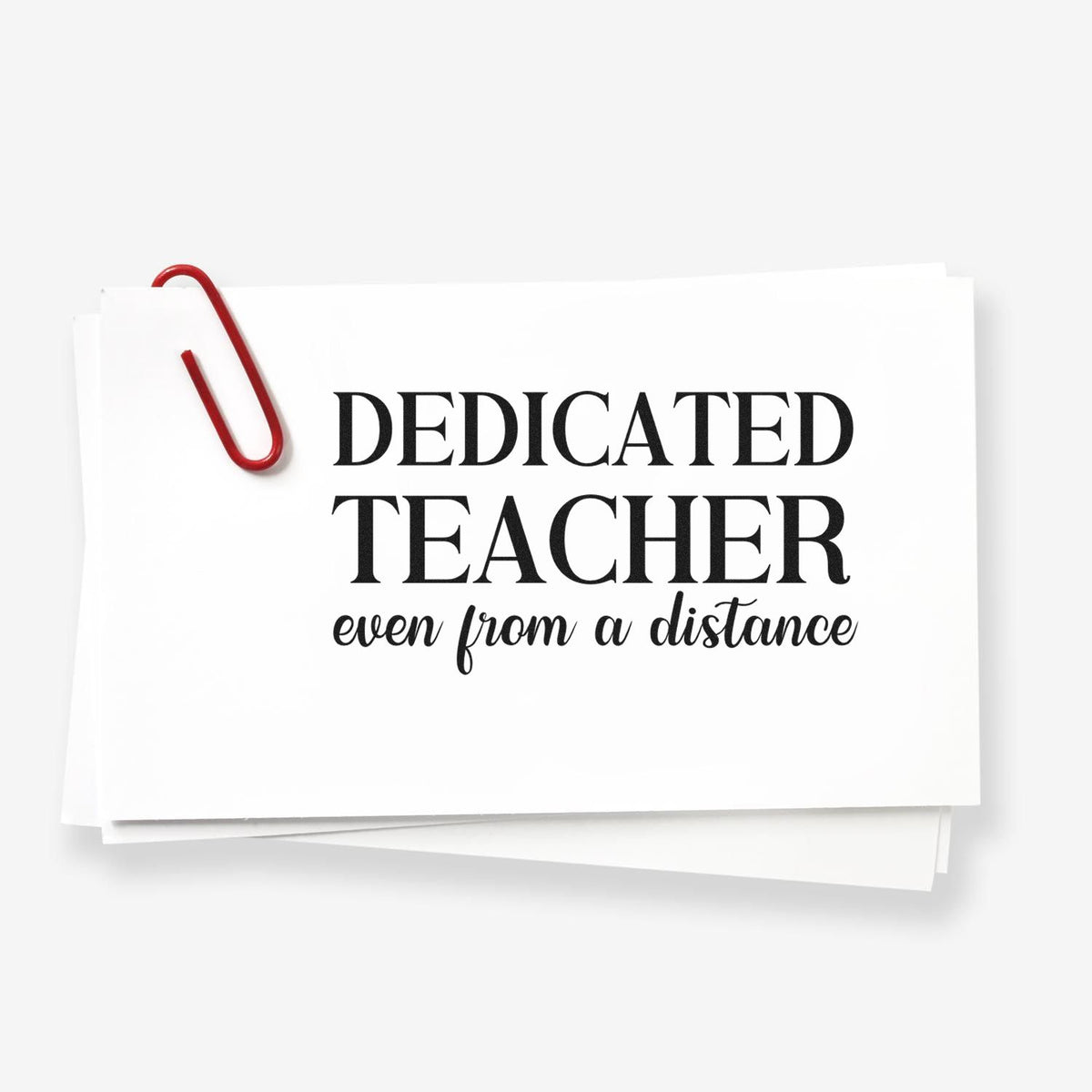 White teacher appreciation stamp seal with red paperclip, reading Dedicated Teacher even from a distance