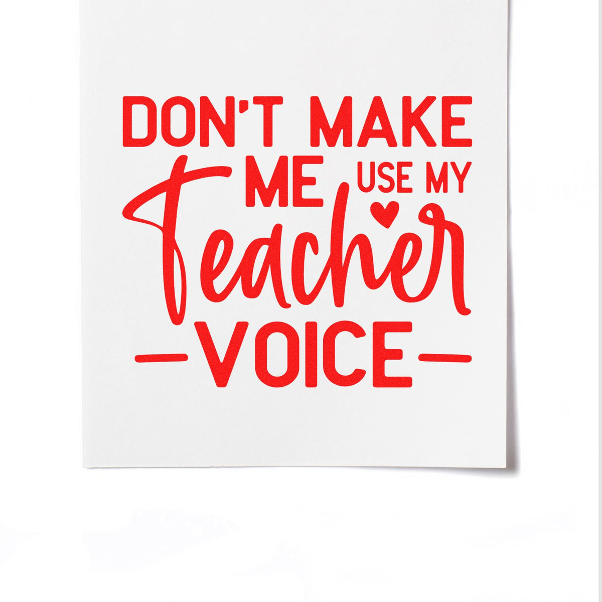 Red teacher stamp/seal on white card with bold red text: Dont make me use my teacher voice and a small heart accent.