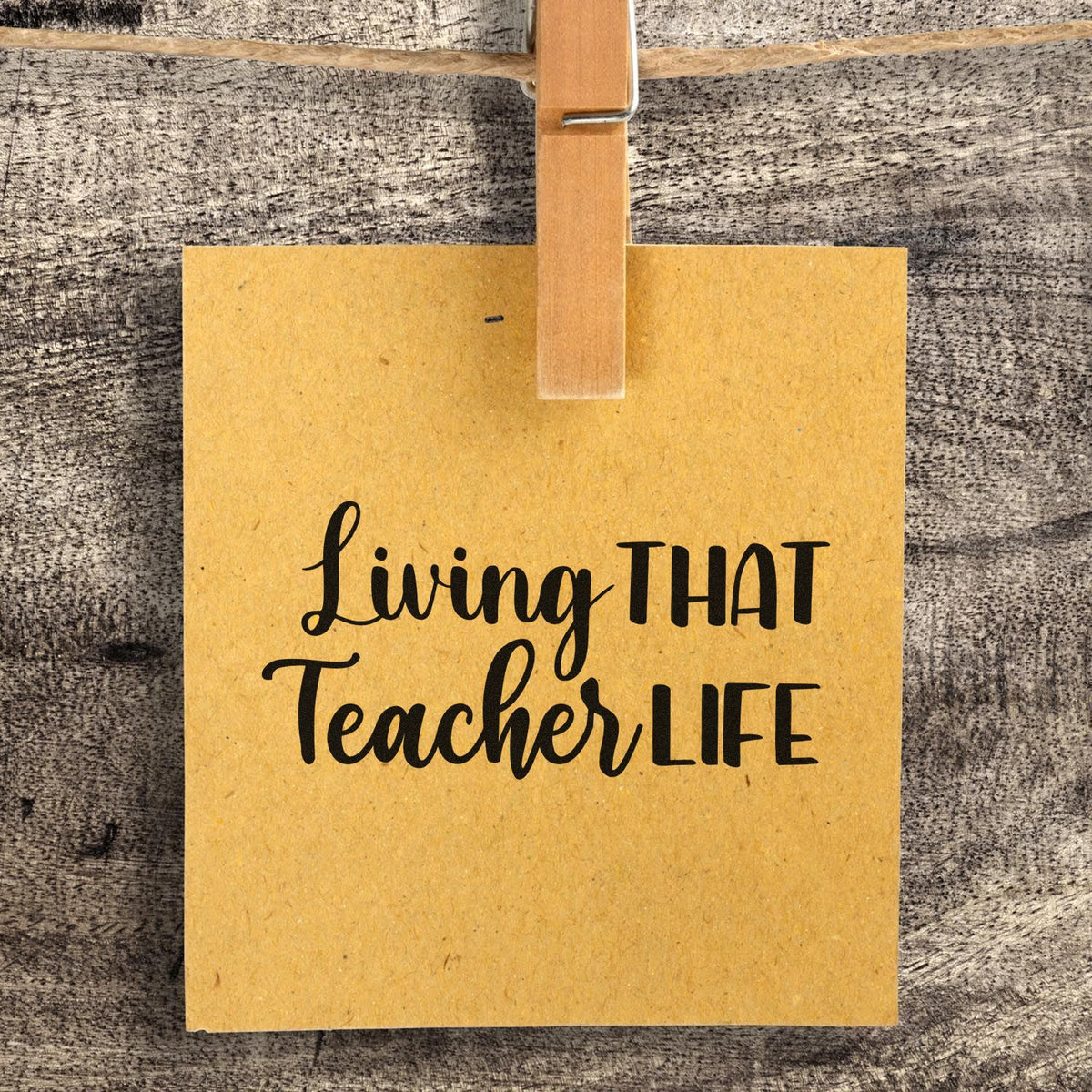 Yellow kraft paper stamp and seal sample with black Living THAT Teacher LIFE text, clipped with a wooden clothespin.