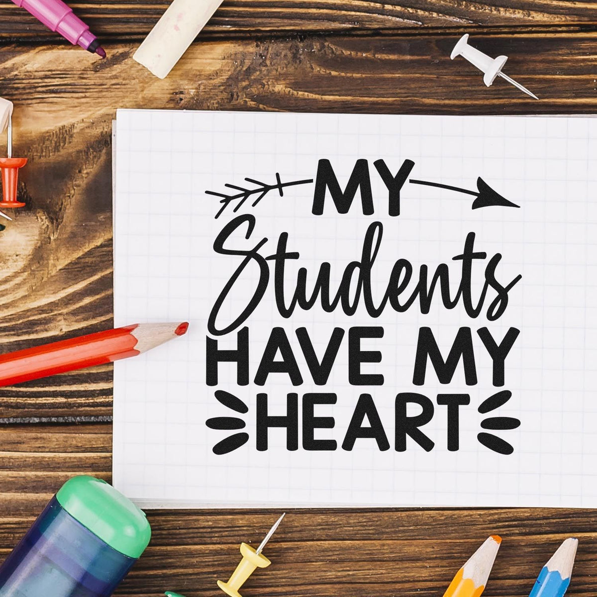 Black My Students Have My Heart custom stamp design on white grid paper, with pencils and colorful stamp/seal tools on wood.