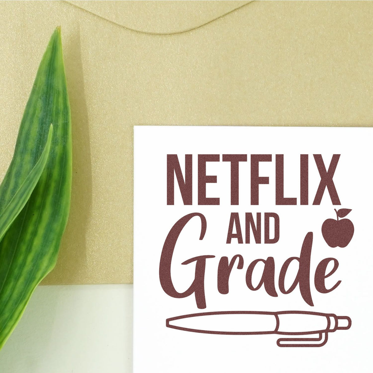 Maroon Netflix and Grade stamp and seal design on white card, with apple icon and pen outline, beside green leaf on gold background