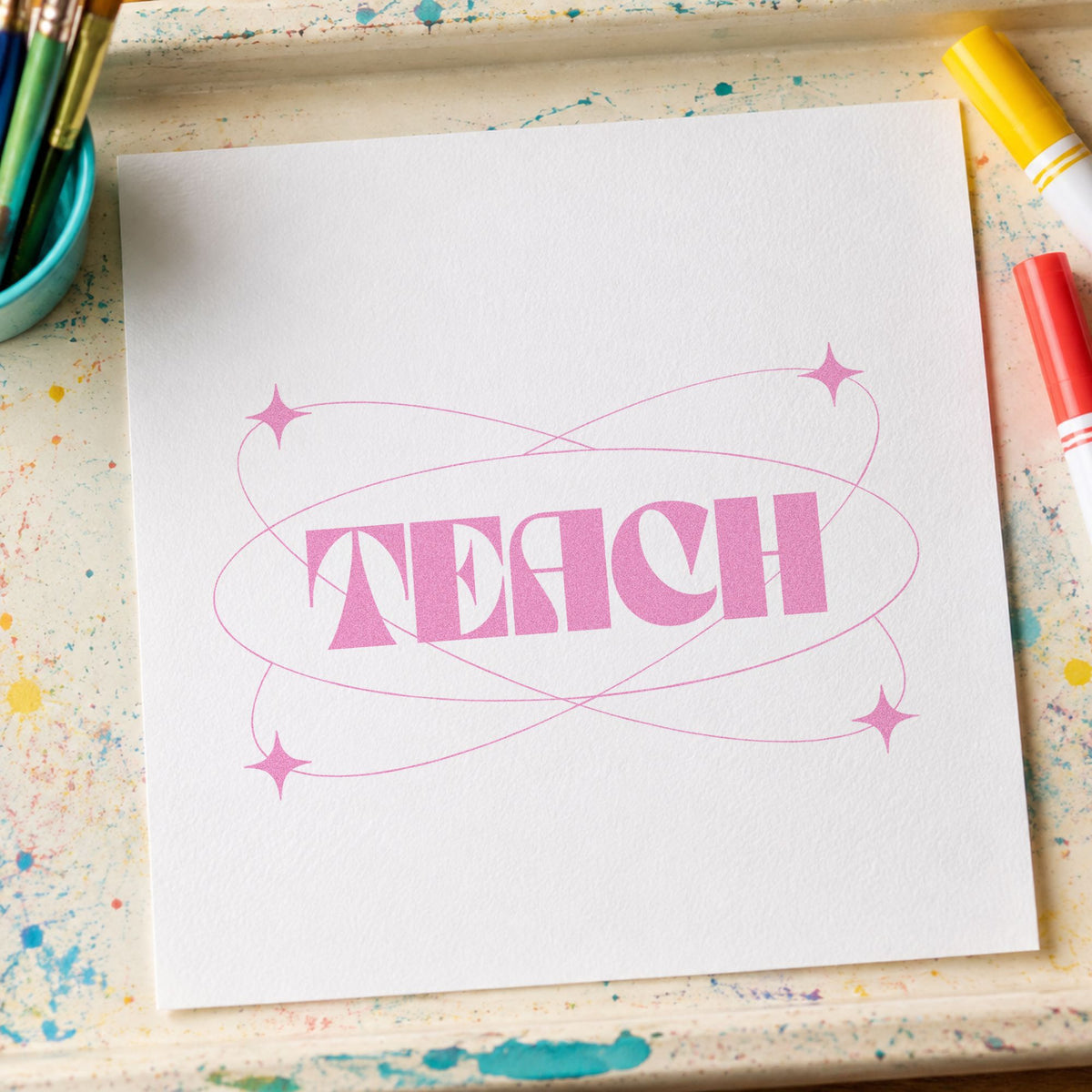 Teach With Orbit Sparkles craft stamp in purple ink on cardstock, an easy option for rocket club tags.