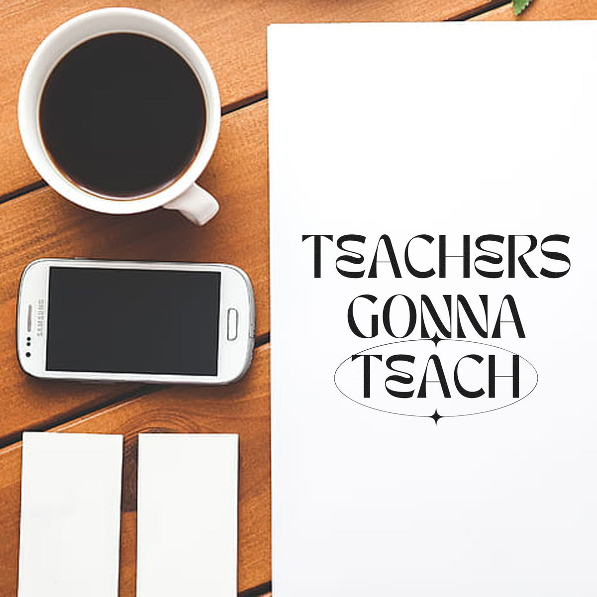 White teacher stamp and seal set with black Teachers Gonna Teach design, plus coffee cup and smartphone on a wood table.