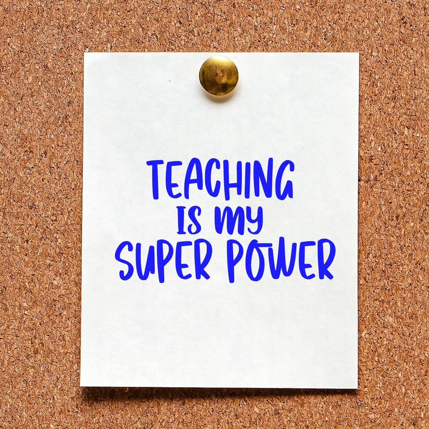 Blue teacher stamp reading Teaching is my super power on white card, pinned with a brass tack to a corkboard.