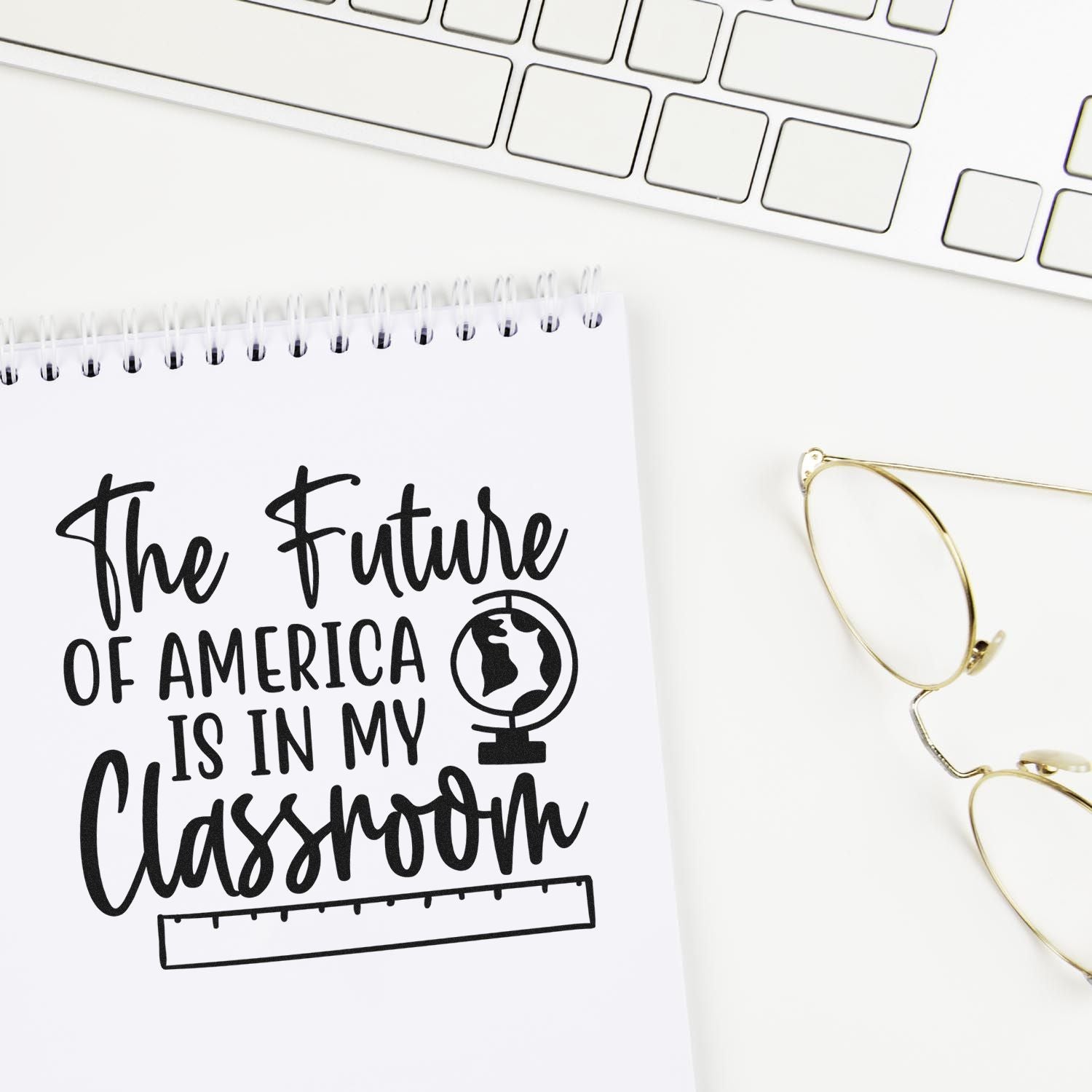 Custom stamp seal on white notepad reading "The Future of America Is in My Classroom," with globe icon, keyboard and gold glasses.
