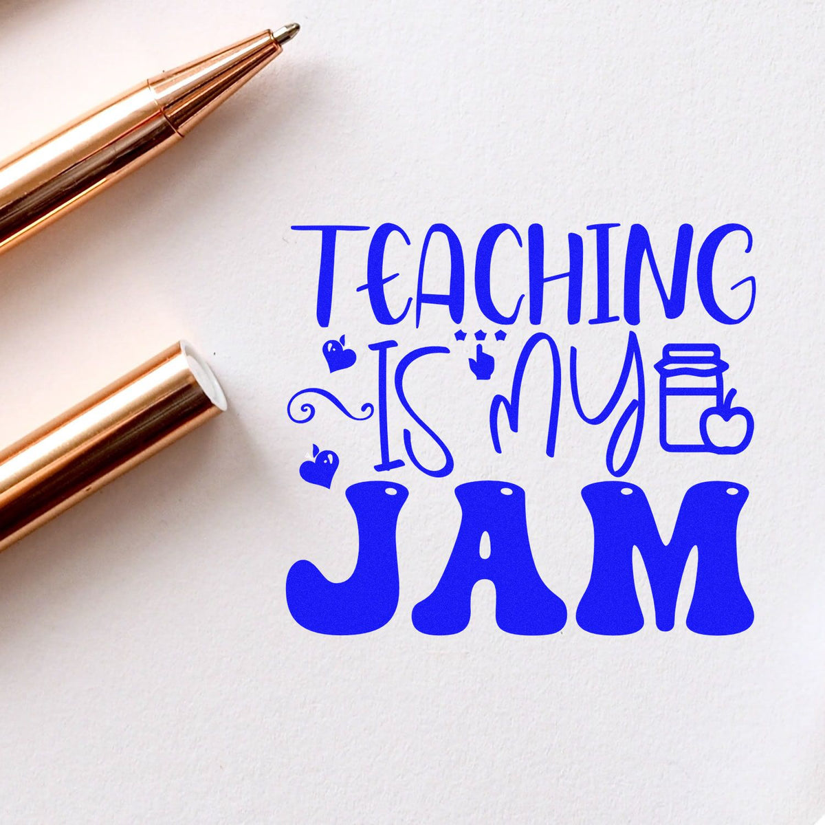 Blue Teaching Is My Jam stamp and seal design with rose gold pens on white paper.