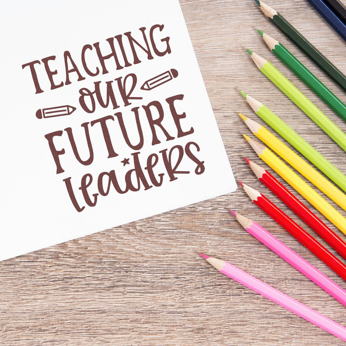 Teaching Our Future Leader stamp/seal design with brown lettering and colorful pencils on white paper