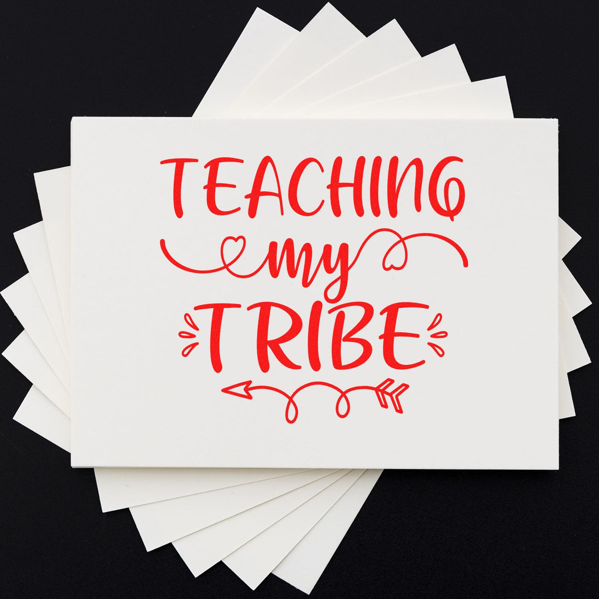 Stacked white stamp and seal cards with red Teaching my Tribe lettering on a black background