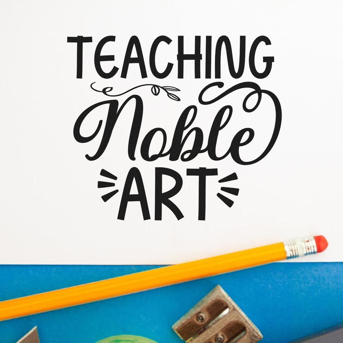 Black Teaching Noble Art stamp seal on white, with yellow pencil, blue background, and art supplies.