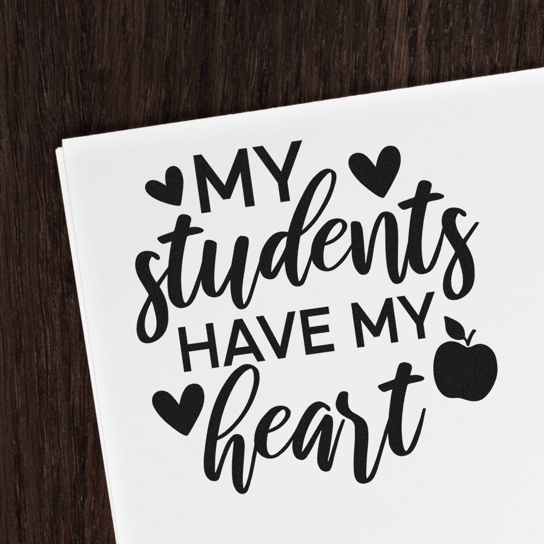 Black stamp-style teacher seal on white paper: My students have my heart with hearts and apple icon.