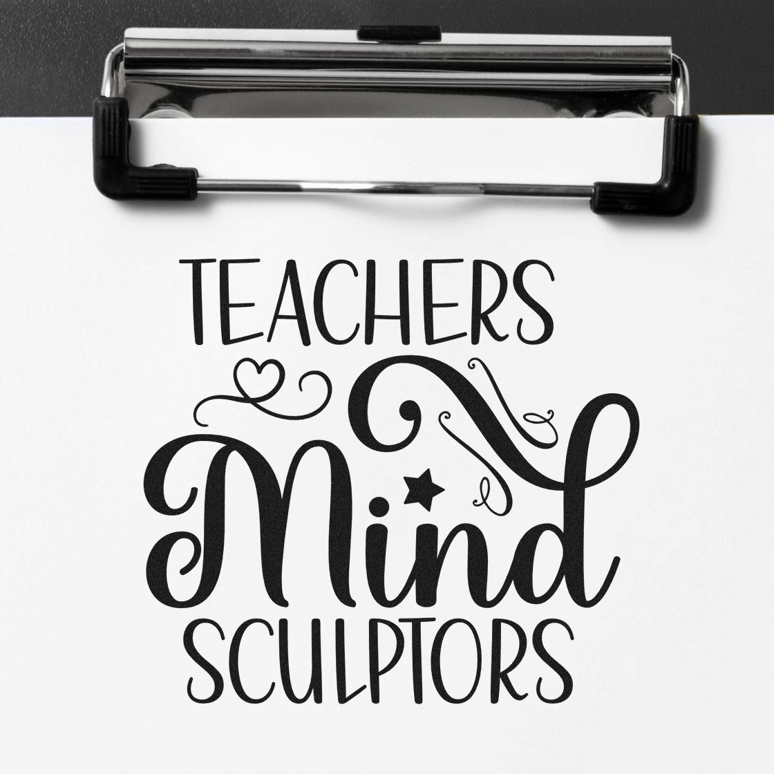 Black teacher stamp and seal on a clipboard with white paper reading Teachers Mind Sculptors in decorative script.