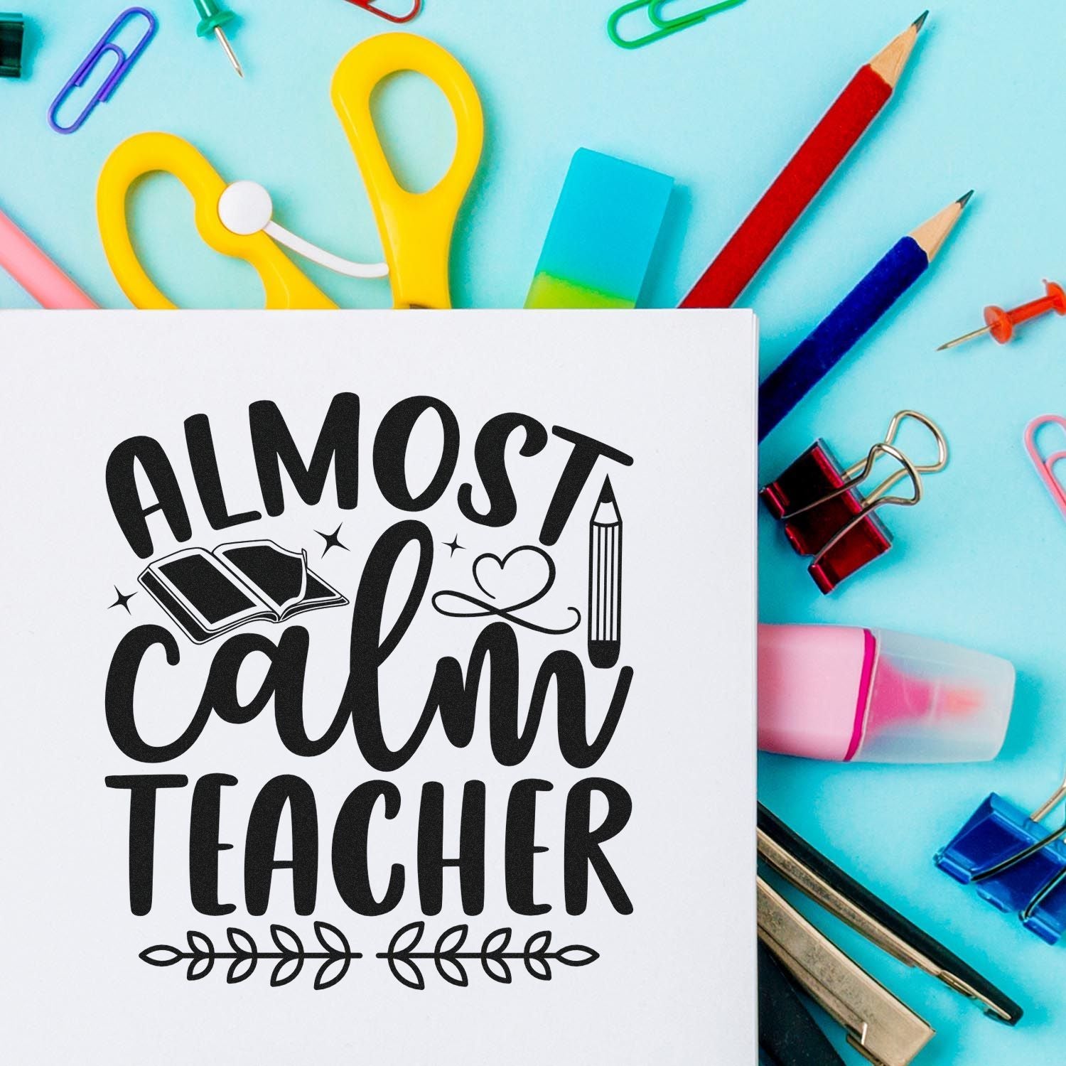 Black Almost Calm Teacher stamp and seal design on white card, with turquoise background, colorful pencils, clips and binder clips.