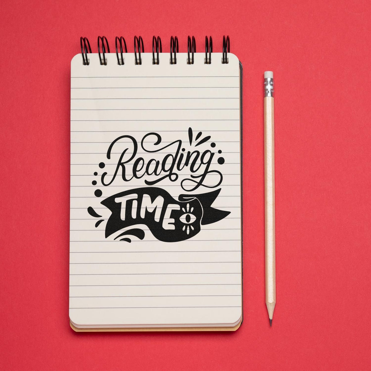 Black Reading Time stamp seal on lined notebook with pencil, set against a bright red background.