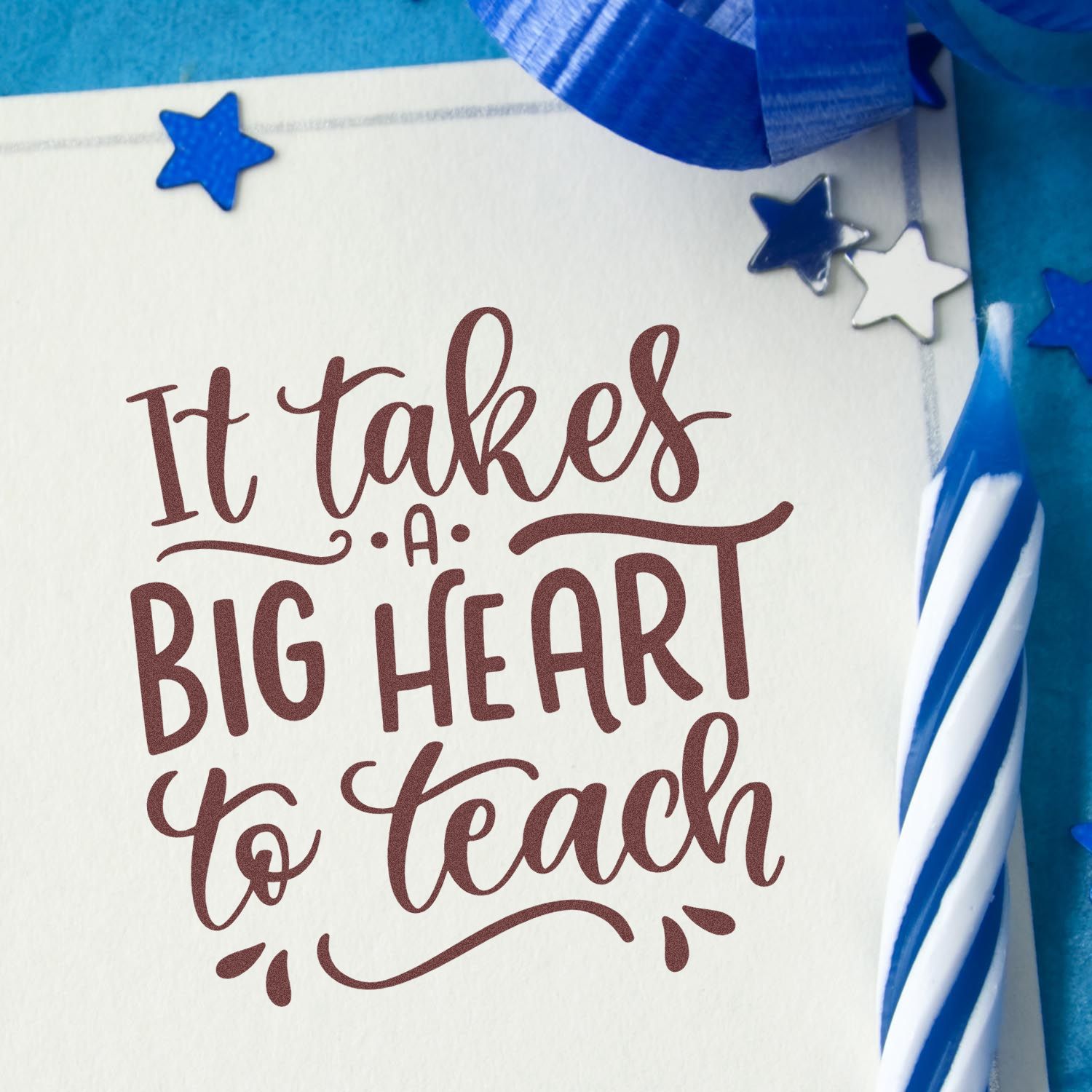 Maroon script stamp saying It takes a big heart to teach on white paper, with blue ribbon and star seal accents.