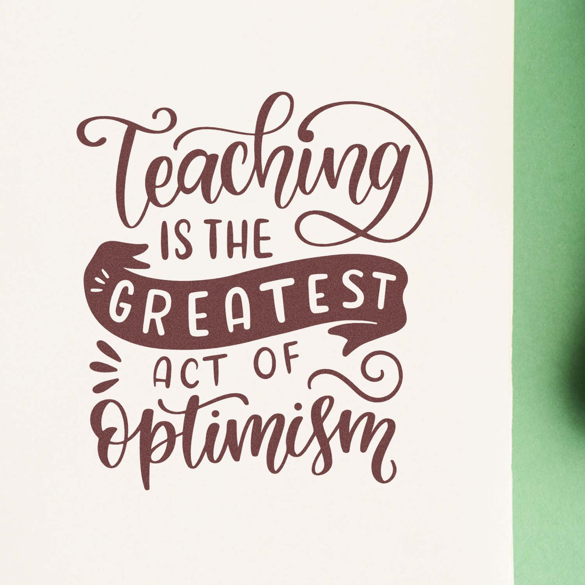 Maroon teaching quote stamp design on white paper with green edge, featuring flowing script and bold seal-style lettering.