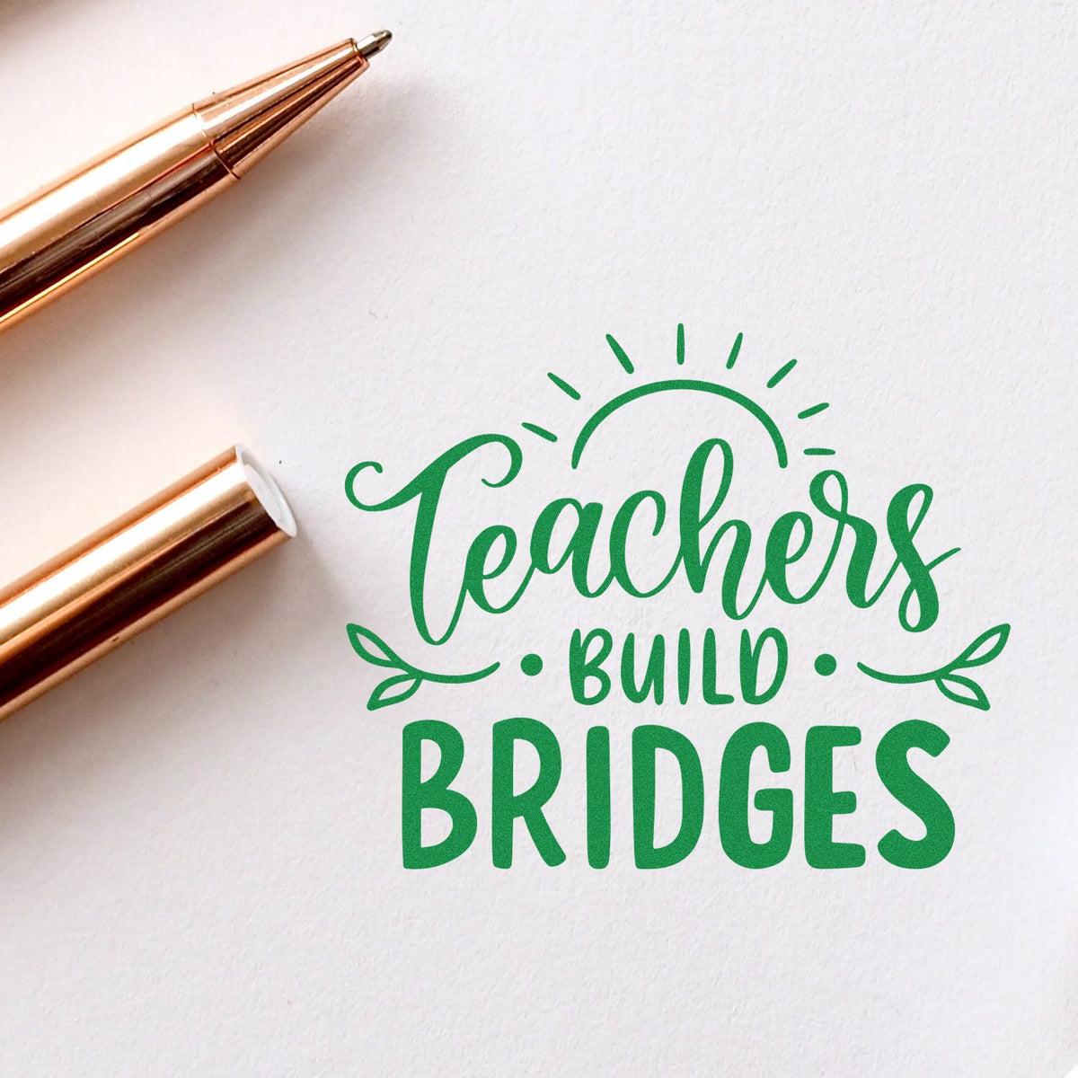 Green Teachers Build Bridges stamp and seal on white paper, with gold pens and sunburst leaf accents.