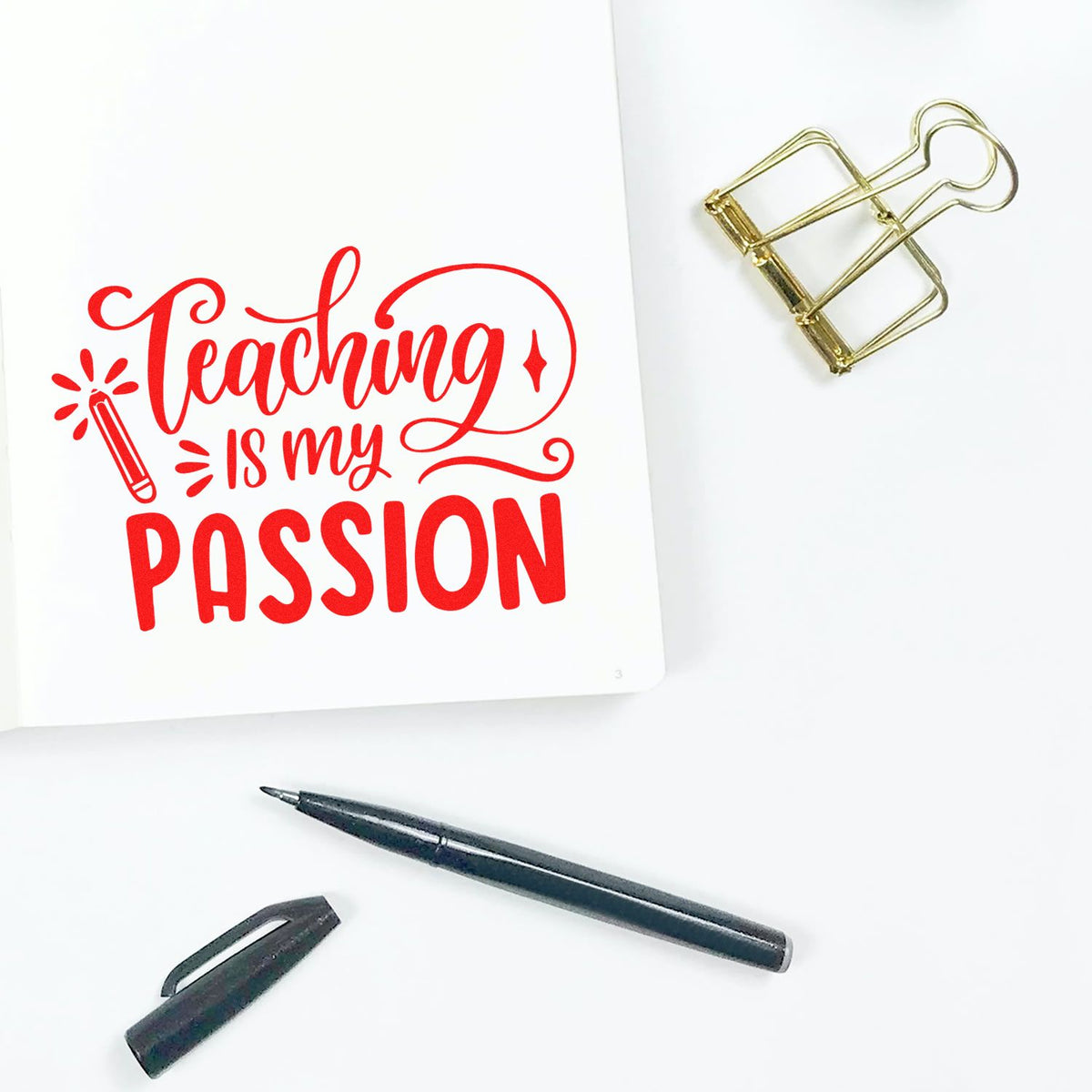 Red teaching-themed stamp on white paper, with gold binder clip, black pen, and pen cap for stamp and seal products.